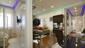 A modern living room with a sofa, a dining table, and a kitchen area with cabinets and a countertop. - Central Station Art Apartment (Split)