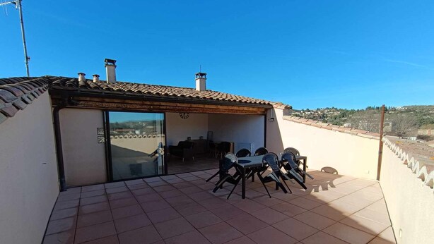 A patio with a table and chairs, a glass door leading inside, and a view of the surrounding landscape. - La Terrasse des Augustins (Limoux)