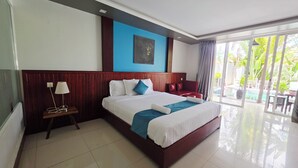 Habitación de hotel con una cama grande, una mesita de noche con lámpara, una pared de acento azul y vistas al exterior.