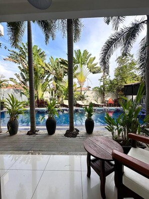 A pool area with potted plants, a wooden table, and lounge chairs. - Angkor Sweet Night Hotel (Siem Reap)