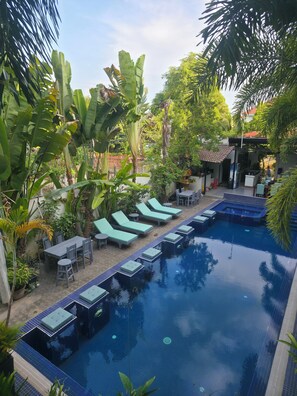A pool area with lounge chairs, a dining table, and a small garden with tropical plants. - Angkor Sweet Night Hotel (Siem Reap)