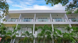 Un edificio de varios pisos con balcones, ventanas amplias y abundante vegetación.