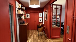 A hallway with wooden flooring, red walls, and a door leading to another room. - Luxury apartment next to the Trocadéro (Paris)