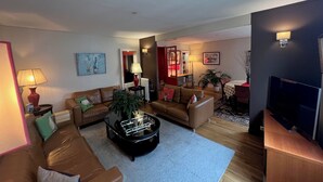 A living room with two sofas, a coffee table, and a TV. There is a plant and a lamp on the coffee table. - Luxury apartment next to the Trocadéro (Paris)