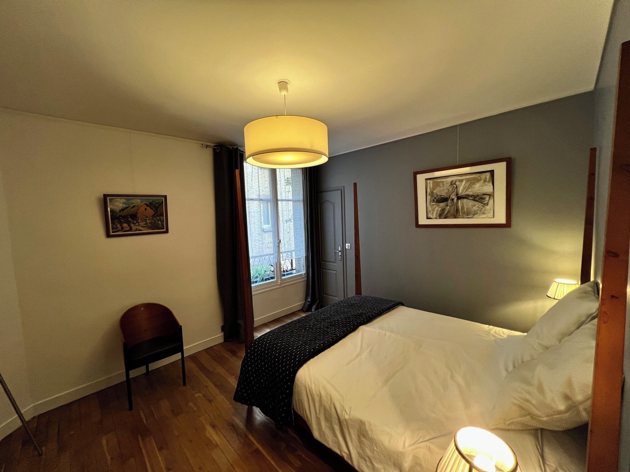 A bedroom with a bed, a chair, a window, and a door.