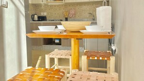 Une cuisine compacte avec un coin repas, comprenant une table en bois et des chaises en osier.