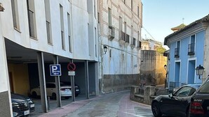 Eine schmale Straße mit parkenden Autos an beiden Seiten, einem Fußweg und Gebäuden unterschiedlicher Architektur.