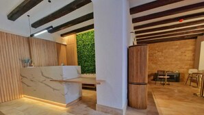 Ein modernes Interieur mit einem Marmor-Rezeptionstresen, Holzvertäfelung, einer grünen Wand und einem Steinfußboden.