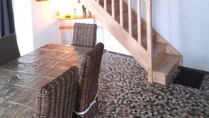 Un comedor con mesa y sillas, una escalera y una pared decorada con cuadros.