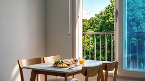 Una mesa de comedor con sillas, un plato de comida, un vaso de jugo de naranja y un bol de fruta.