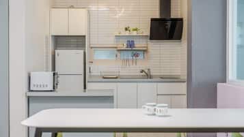Una cocina moderna con armarios blancos, microondas integrado, refrigerador y campana extractora negra.