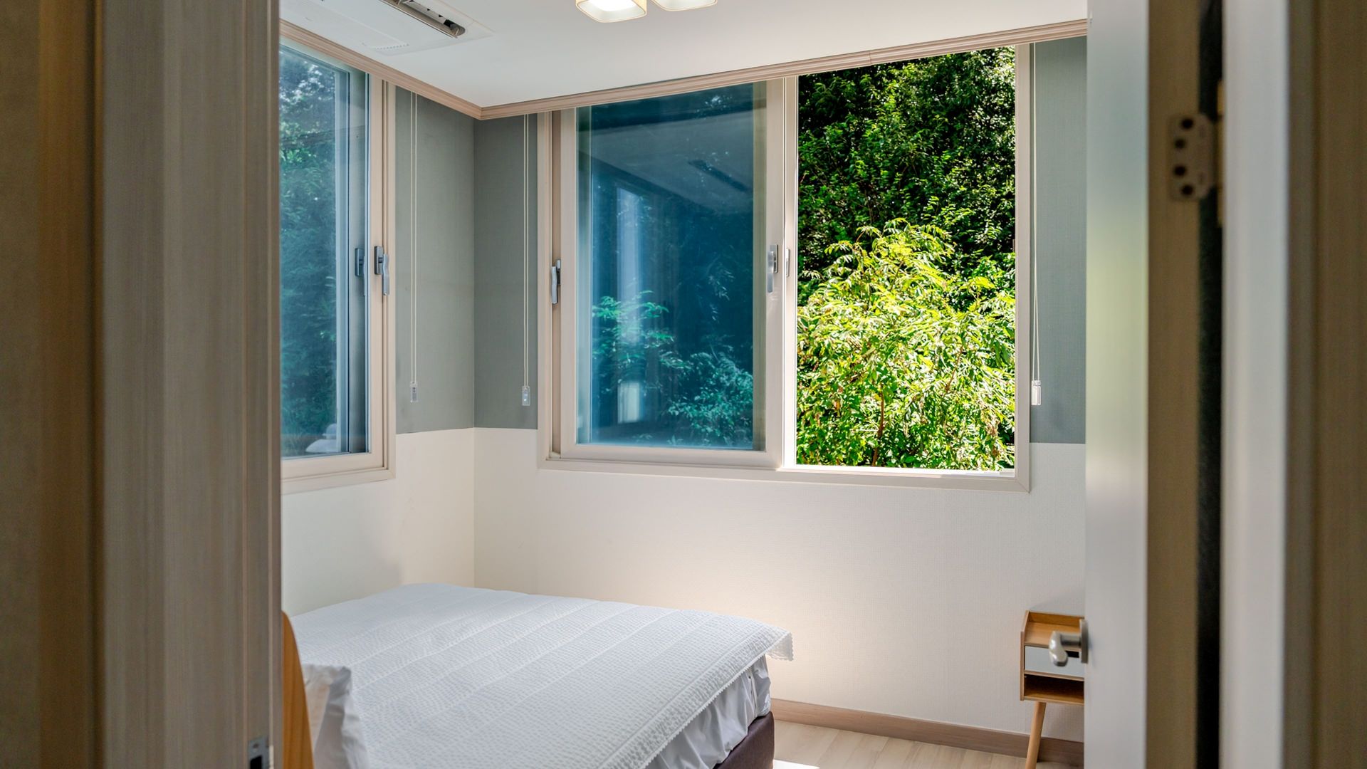 A bedroom with a bed, a window, and a small bedside table.