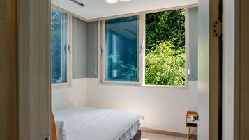 A bedroom with a bed, a window, and a small bedside table.