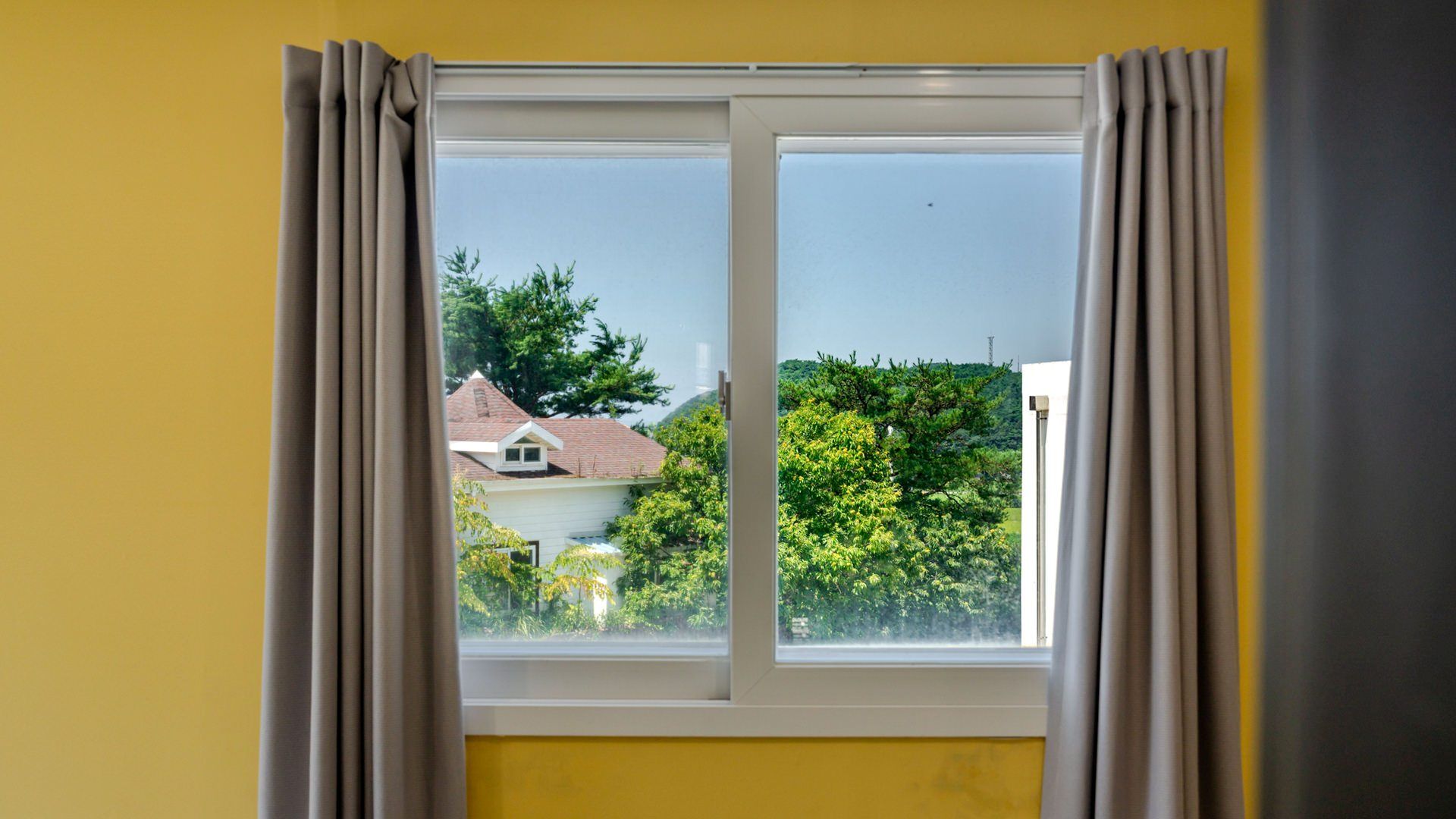 Una ventana con vista a una casa y árboles.