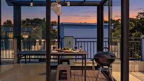 A balcony with a table set for dining, a grill, and a fan. - Taean Blueisland Pool Villa (Taean)