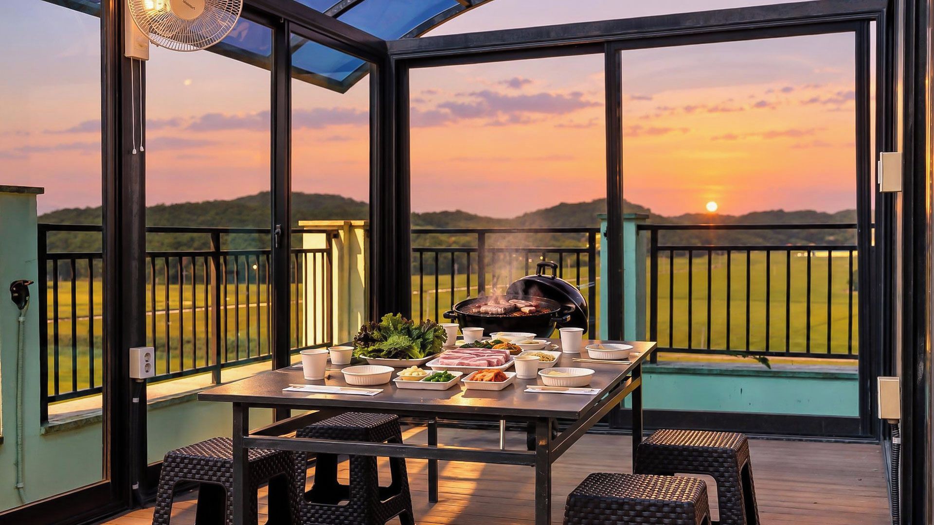 Ein Essbereich im Freien mit einem für eine Mahlzeit gedecktem Tisch, einem Grill und einem malerischen Sonnenuntergangsblick.