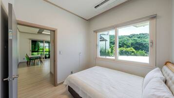 Un dormitorio con un ventanal, una cama y vistas a zonas verdes.