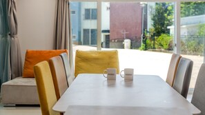 A modern interior with a dining table, chairs, and a sofa with cushions. Two white mugs are placed on the table. - Taean Blueisland Pool Villa (Taean)