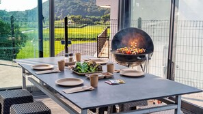 An outdoor dining area with a grill, table set with plates, cups, and a salad. - Taean Blueisland Pool Villa (Taean)