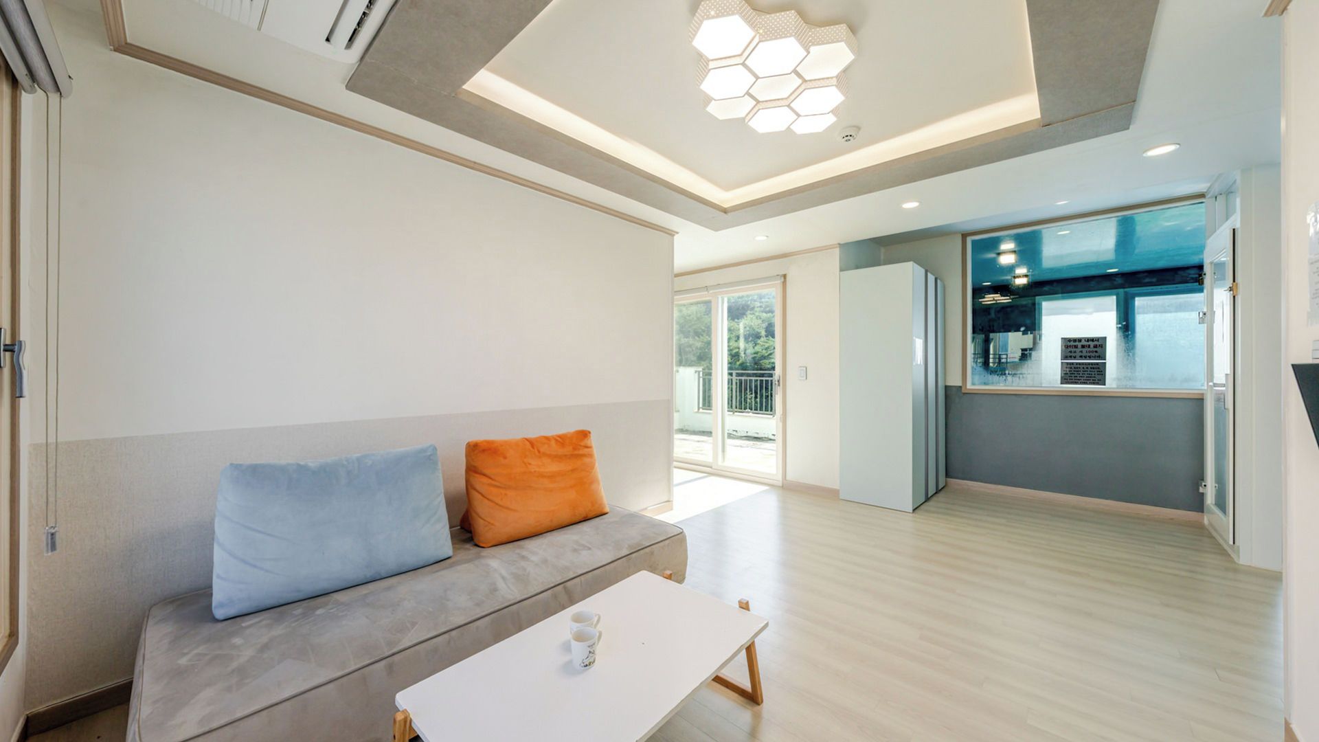 A modern living room with a sofa, a coffee table, and a view to an outdoor area.