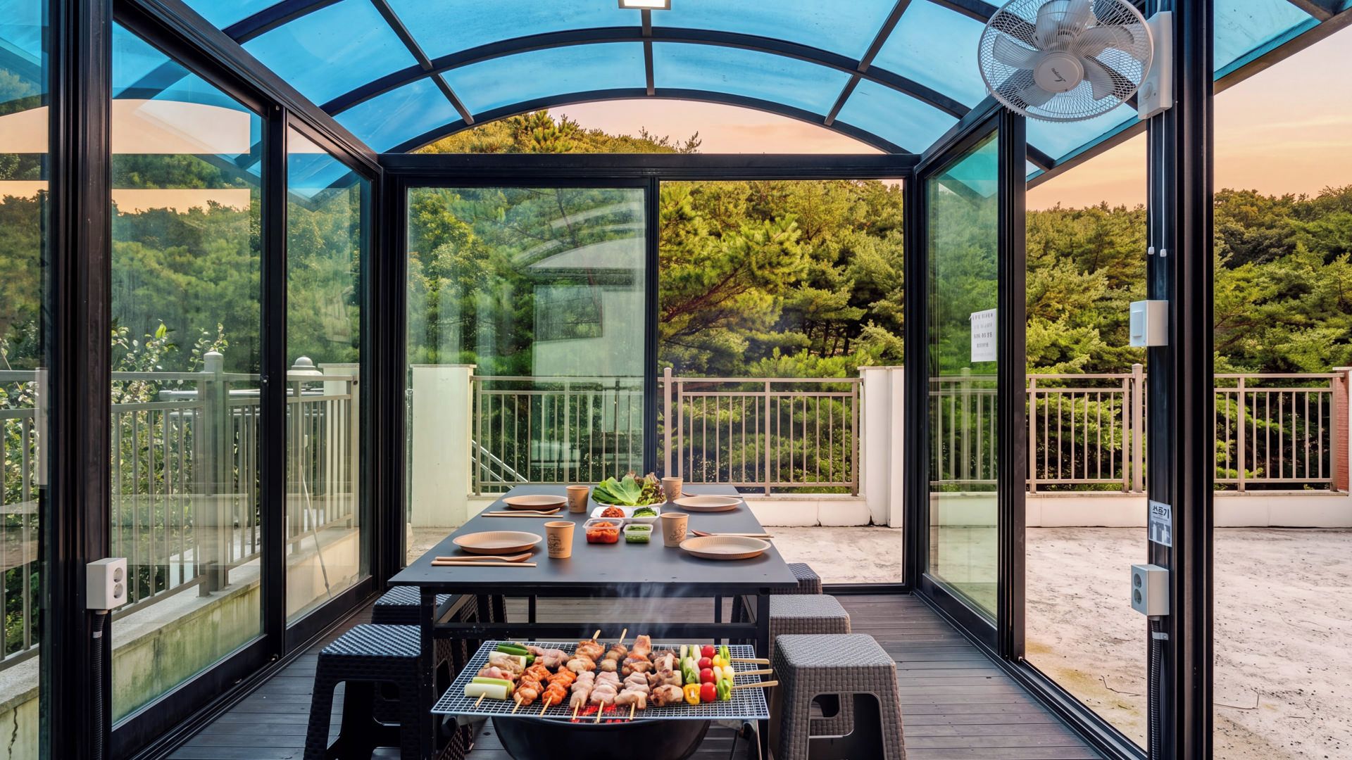 A covered outdoor dining area with a grill, tables, and chairs.