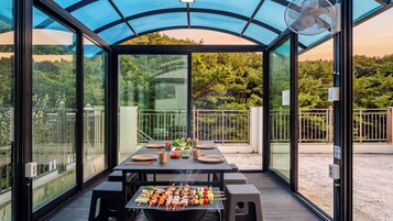 Un espacio al aire libre techado con zona de comedor, una parrilla, mesas y sillas.