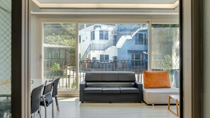 Una sala de estar moderna con un sofá, sillas y vistas a un edificio con escaleras.