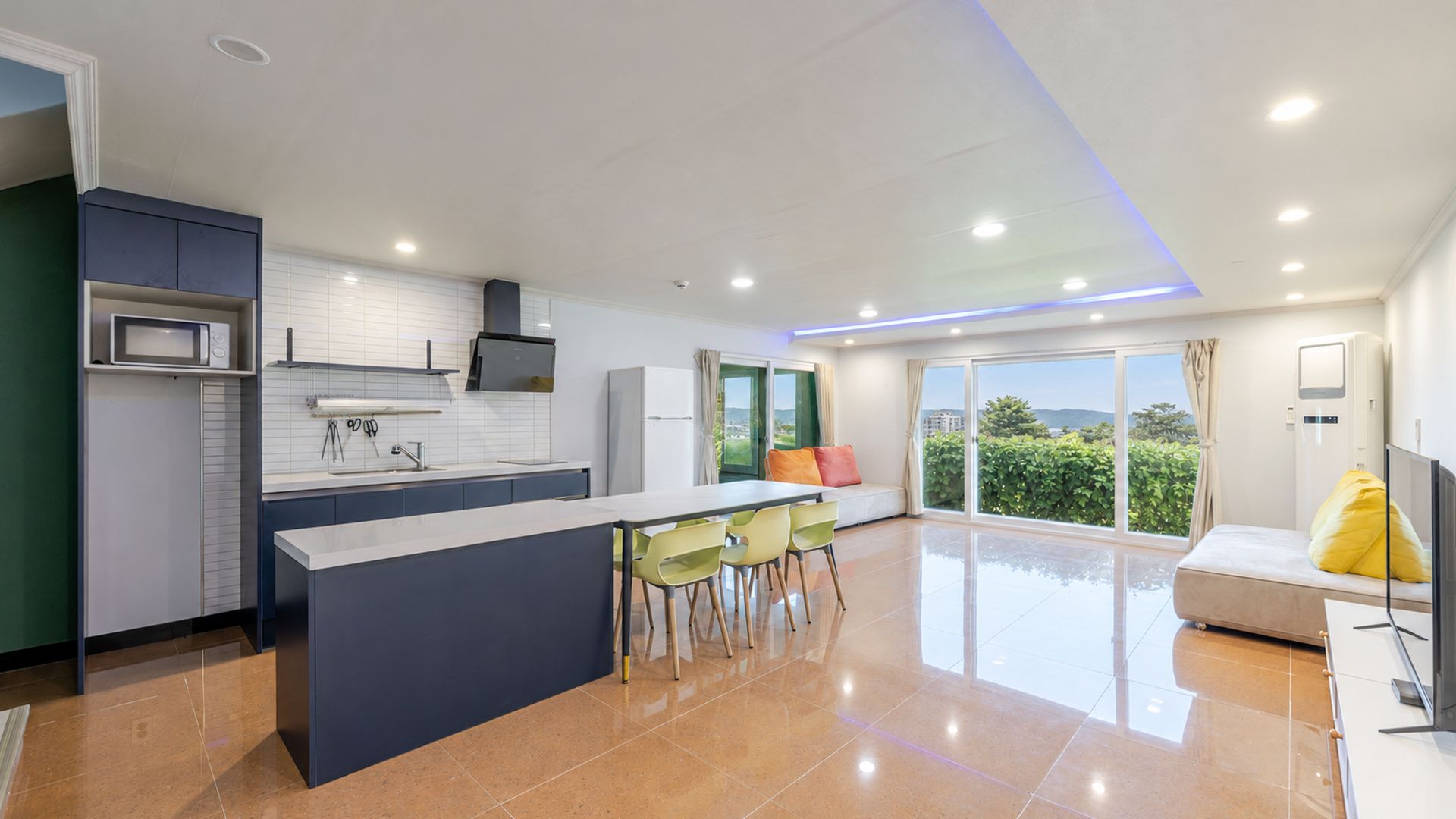Una cocina moderna con una isla central, comedor con sillas y un sofá con vistas.
