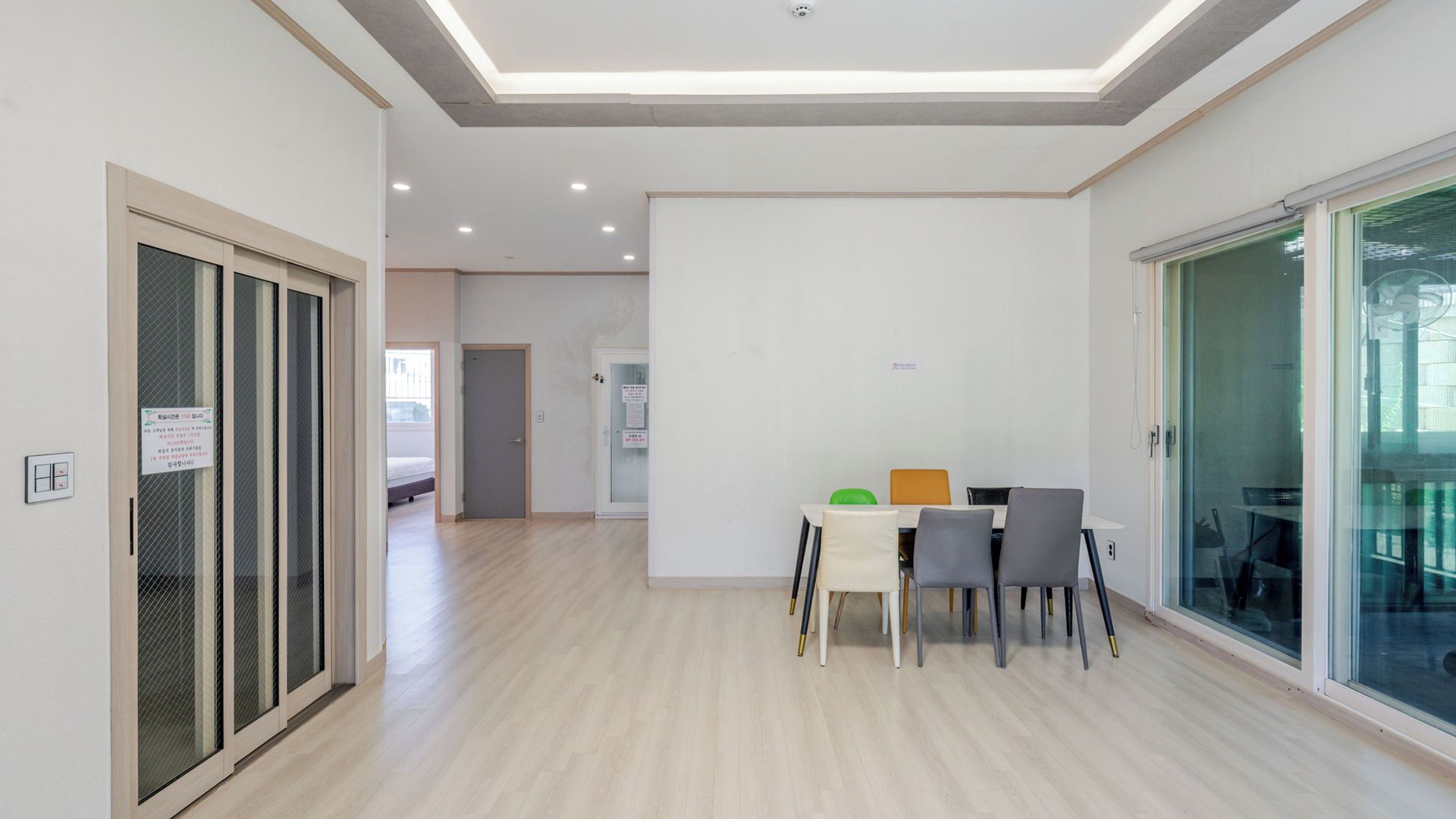 A modern interior with a dining area, a sliding glass door, and a hallway leading to another room.