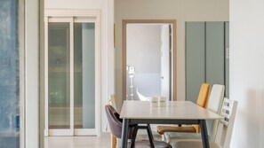 A modern dining area with a table and chairs, a sliding glass door, and a view into another room. - Taean Blueisland Pool Villa (Taean)