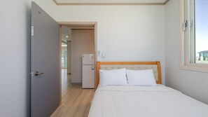 A hotel room with a bed, a door, a refrigerator, and a window. - Taean Blueisland Pool Villa (Taean)