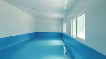 A room with a blue floor, white walls, and large windows.