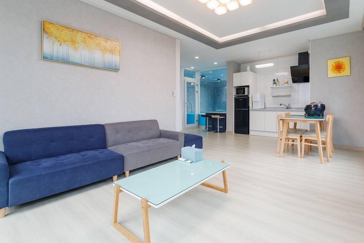 A modern living room with a sofa, a coffee table, and a dining area with a table and chairs.