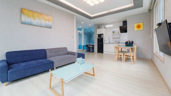 A modern living room with a sofa, a coffee table, and a dining area with a table and chairs. - Taean Blueisland Pool Villa (Taean)