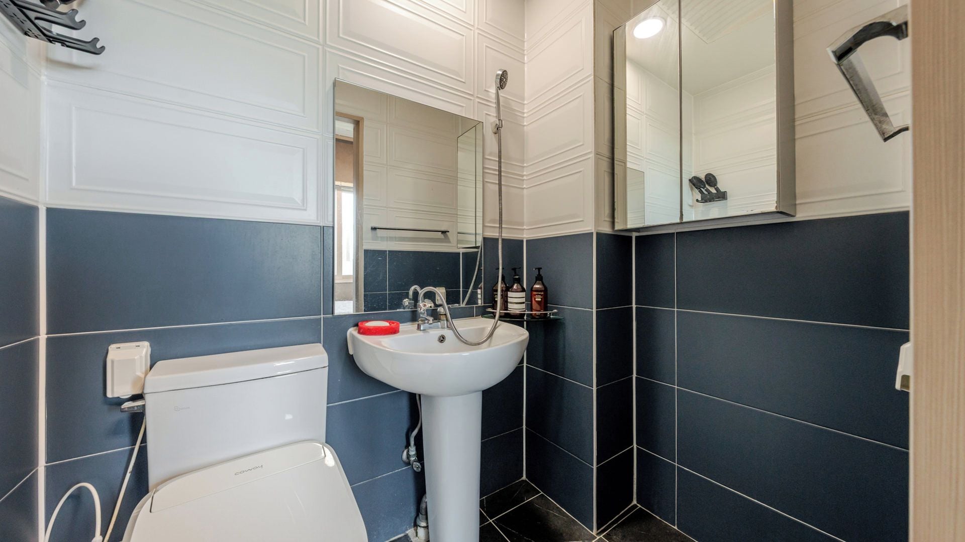 Une salle de bain avec des toilettes blanches, un lavabo et une douche.