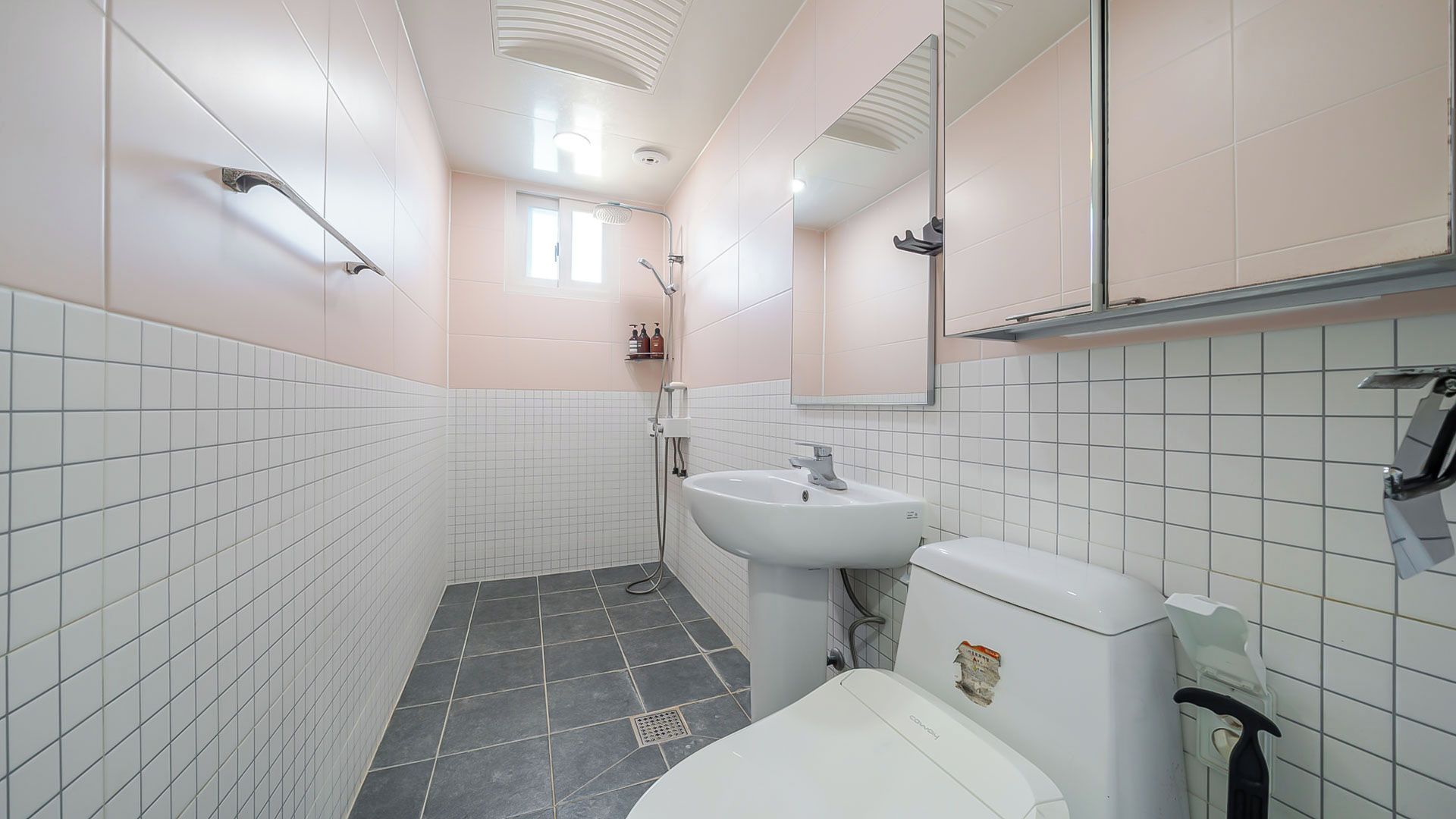 Un baño con azulejos blancos, un lavabo, un inodoro y una ducha.