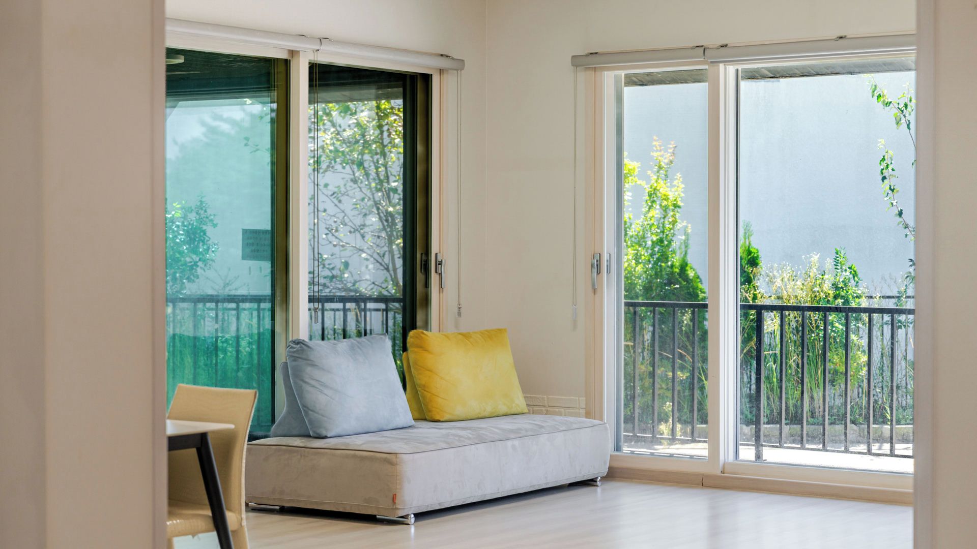 A room with a sofa, a chair, and a sliding glass door leading to an outdoor balcony.