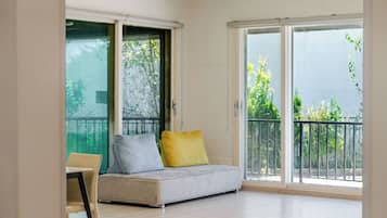 Una habitación con sofá, sillón y puerta corrediza de vidrio que da a un balcón exterior.