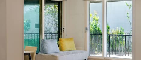 A room with a sofa, a chair, and a sliding glass door leading to an outdoor balcony.