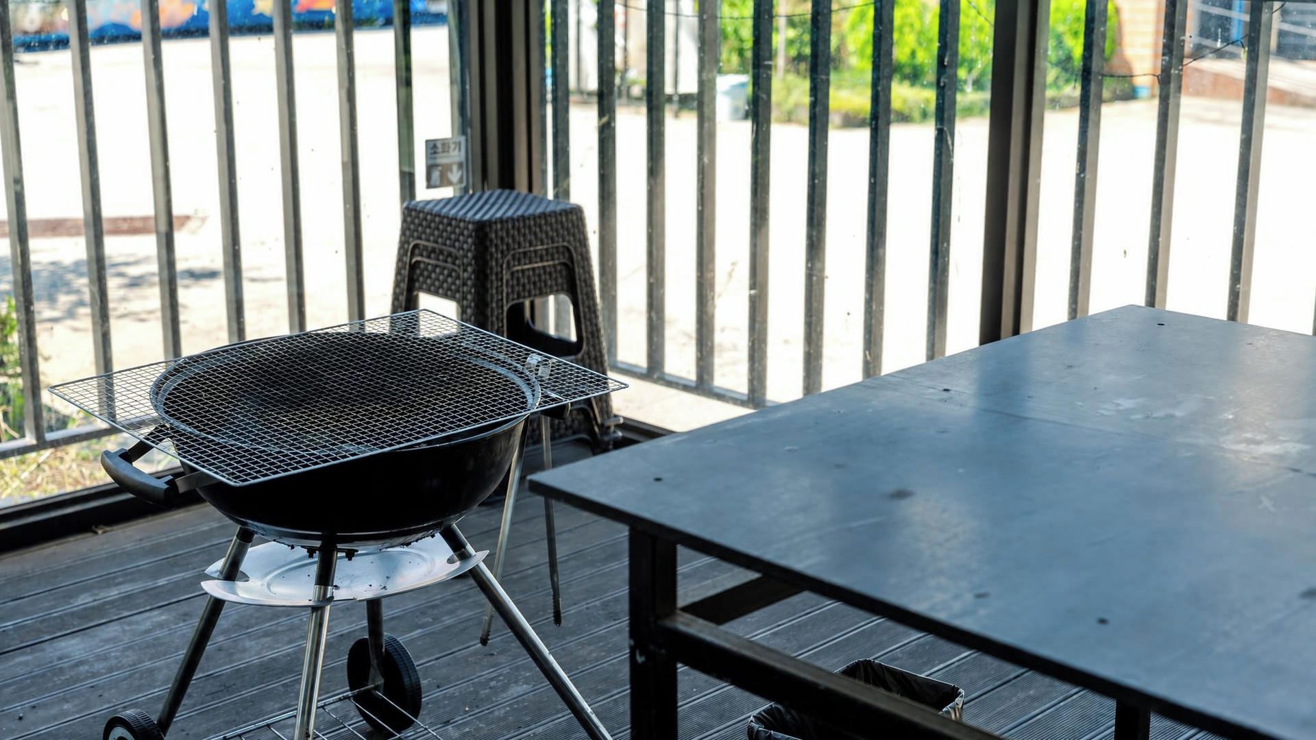 Una parrilla para barbacoa en un patio con una mesa y sillas de metal.
