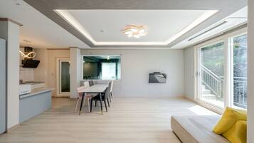 Ein modernes Interieur mit Essbereich, Küche und großen Fenstern.