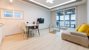 A modern living room with a dining area, a sofa, and a balcony with a view. - Taean Blueisland Pool Villa (Taean)