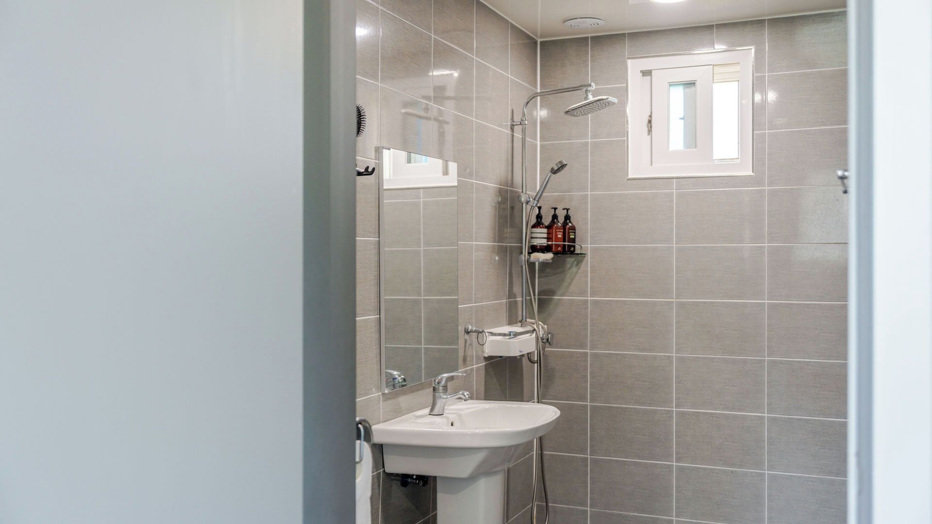 A modern bathroom with a shower, a sink, and a mirror.