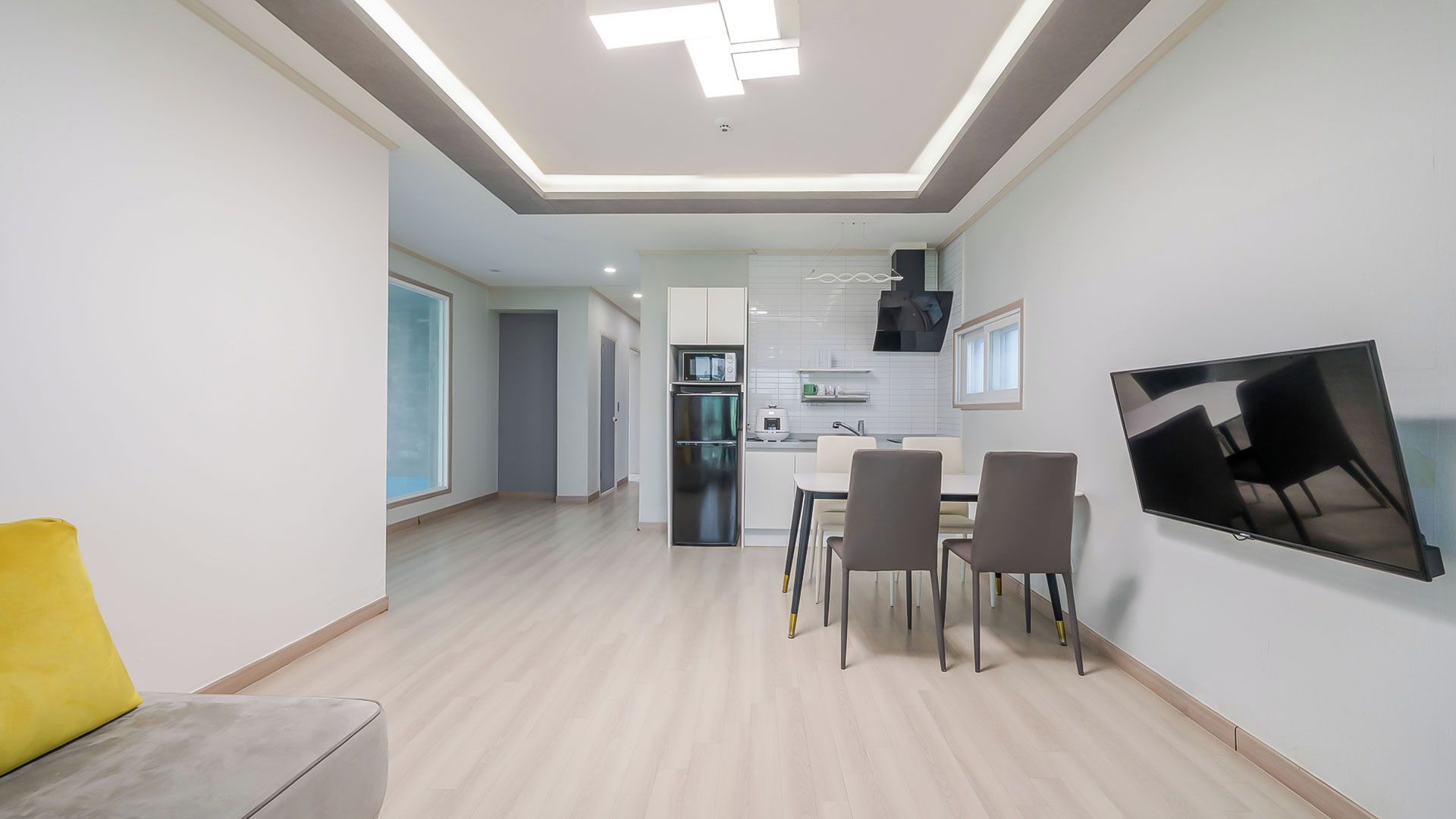 A modern kitchen with a built-in oven, microwave, and a flat-screen TV mounted on the wall.