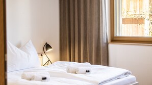 Una habitació d'hotel amb un llit ben arropat, una làmpada de nit i una finestra amb cortines.