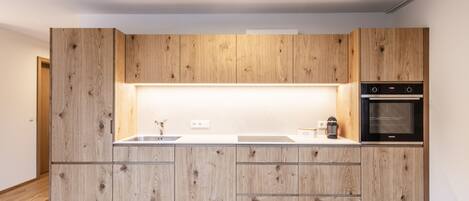 Une cuisine moderne avec des meubles en bois, un four encastré et un plan de travail doté d’un évier.