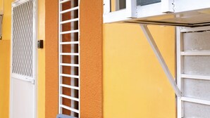 A small outdoor seating area with a table and two chairs, a metal gate, and a window with a screen. - A comfy retreat in the heart of Orani, Bataan (Orani)