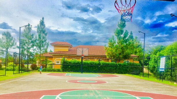 An outdoor basketball court with a net, surrounded by a fence and trees. - A comfy retreat in the heart of Orani, Bataan (Orani)