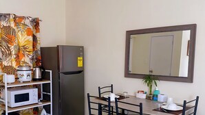 A compact kitchen with a refrigerator, microwave, and a small shelf with kitchen appliances. - A comfy retreat in the heart of Orani, Bataan (Orani)