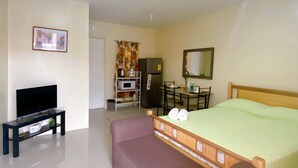 A modern bedroom with a bed, a TV, a sofa, a dining table, and a kitchen area. - A comfy retreat in the heart of Orani, Bataan (Orani)
